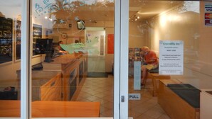 Un mostrador de recepción con un cartel para Crocodilly Inn, horario de recepción y un letrero extraíble.
