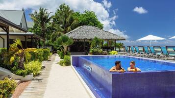 Een buitenzwembad, ligstoelen bij het zwembad