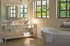 A modern bathroom with a large bathtub, a double sink vanity, and a large mirror.