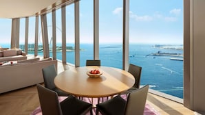 A modern room with a large window, a round table with chairs, a sofa, and a bowl of fruit. - Rixos Premium Dubai JBR (Dubai)