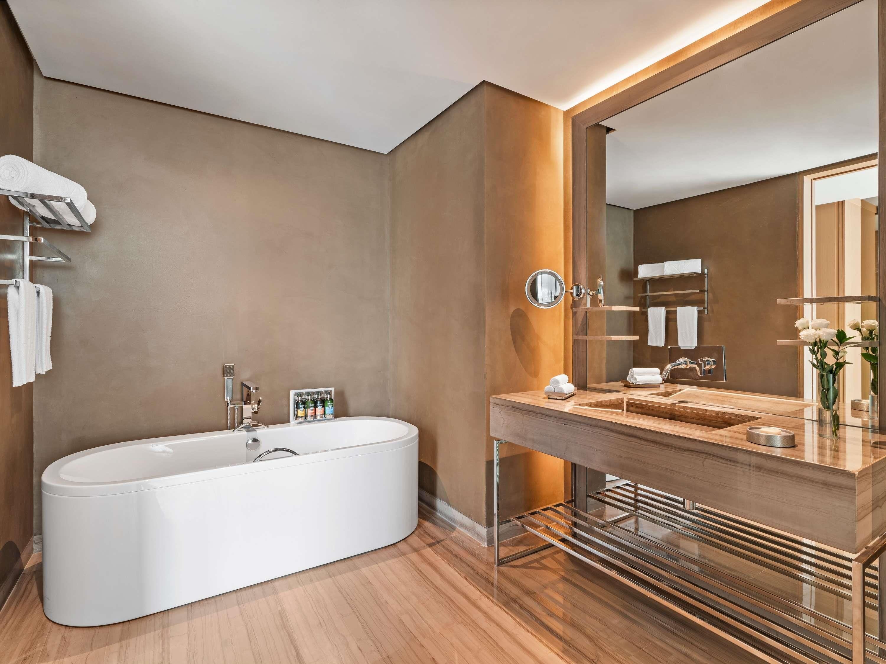 A modern bathroom with a freestanding bathtub, a vanity with a mirror, and a towel rack.