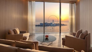 Una camera d'albergo moderna con un'ampia finestra che si affaccia su una ruota panoramica e sulla città al tramonto.