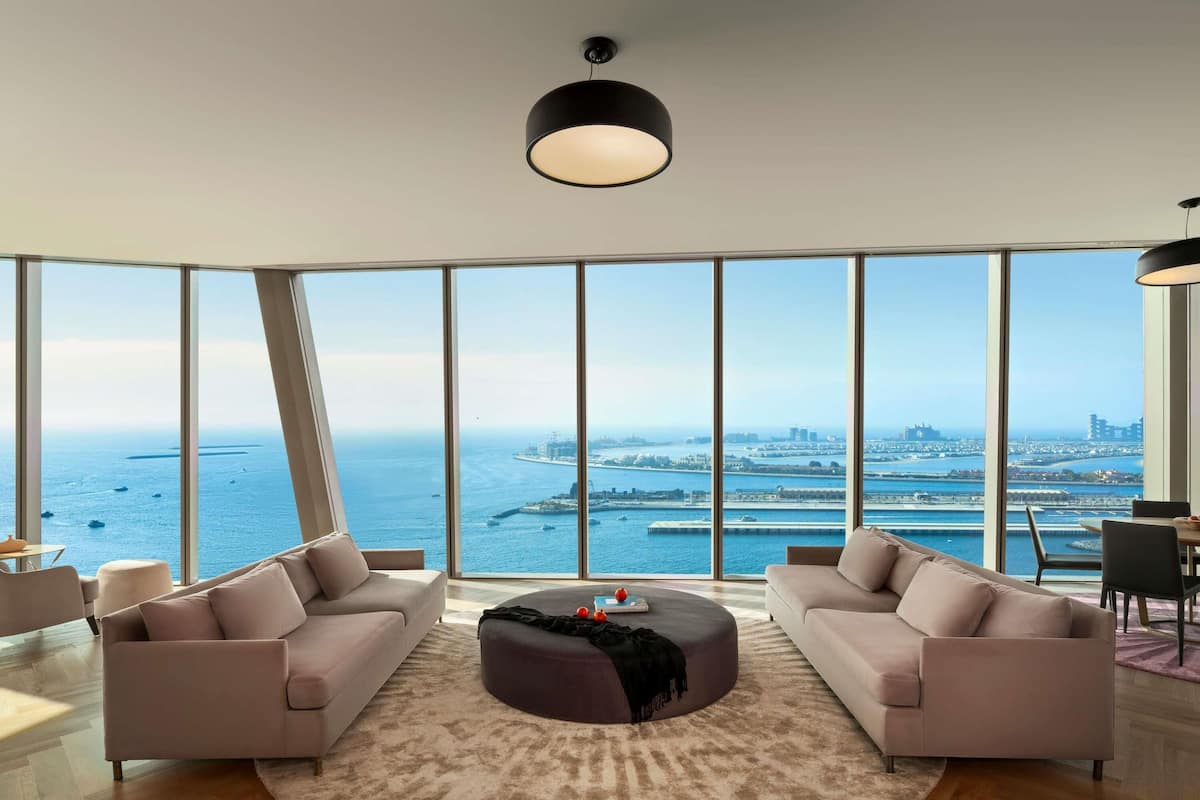 A modern living room with large windows, a round coffee table, and two sofas.