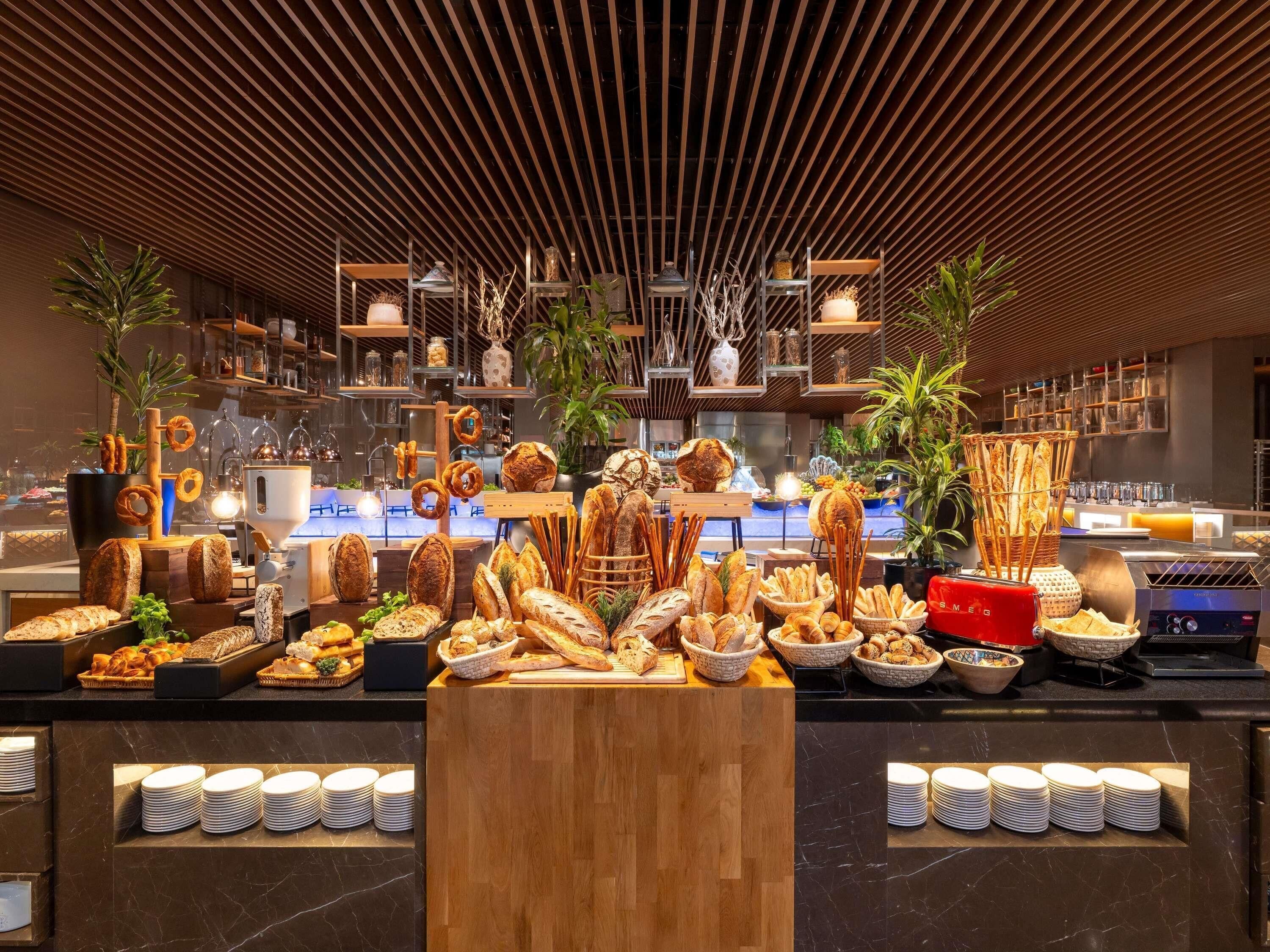Eine Bäckereiauslage mit verschiedenen Brotsorten und Gebäck, Holzregale und hängenden Lampen.