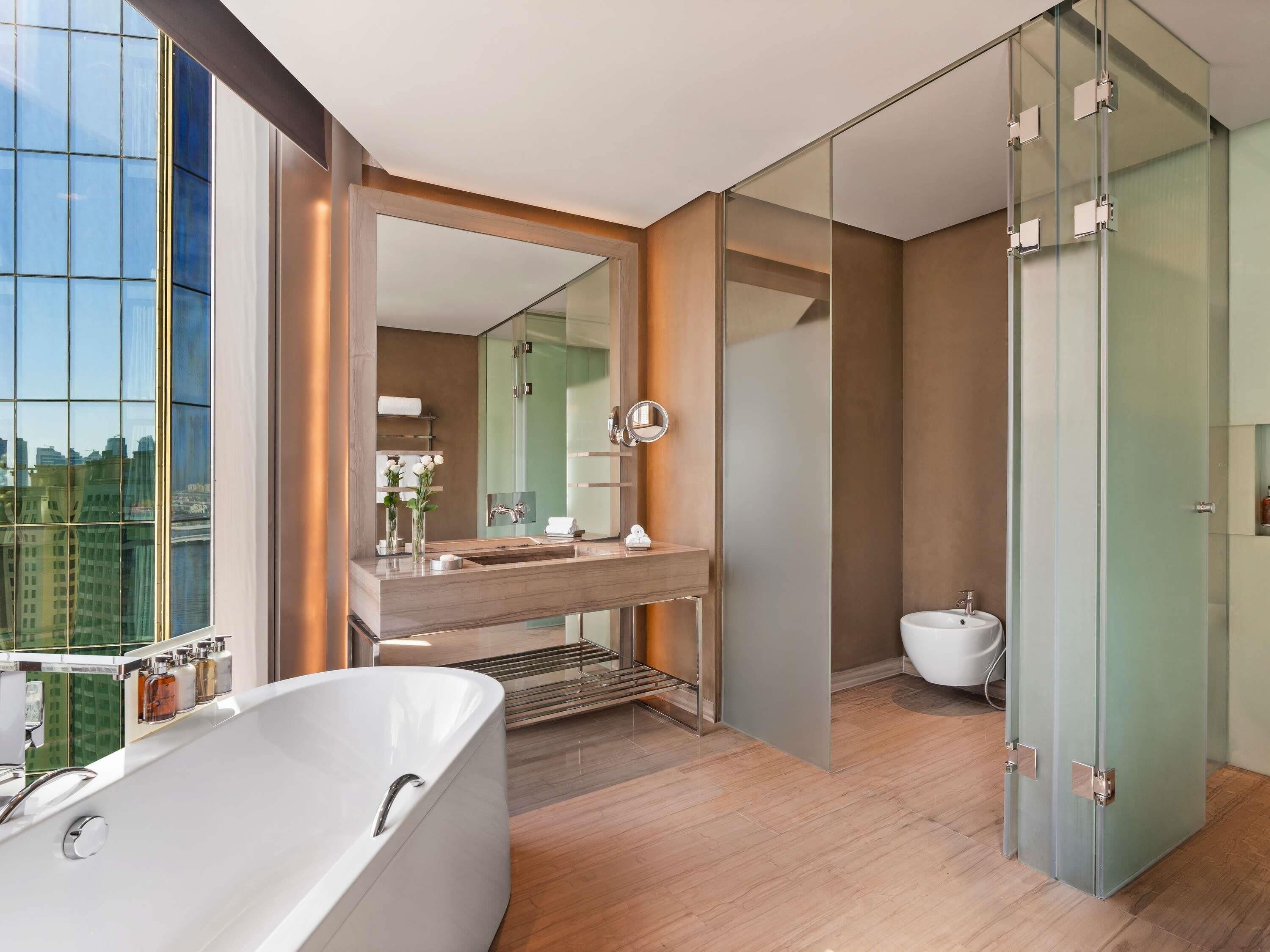 Et moderne badeværelse med badekar, vask, toilet og glasbadevægsafskærmning.