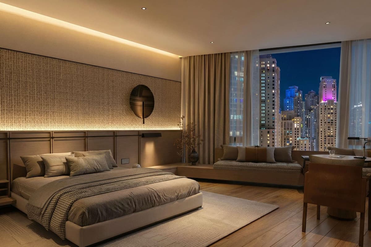 A modern bedroom with a large bed, a seating area, and a city view.