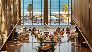 A spacious lobby with a large glass window offering a view of a pool area and the sea. - Rixos Premium Dubai JBR (Dubai)