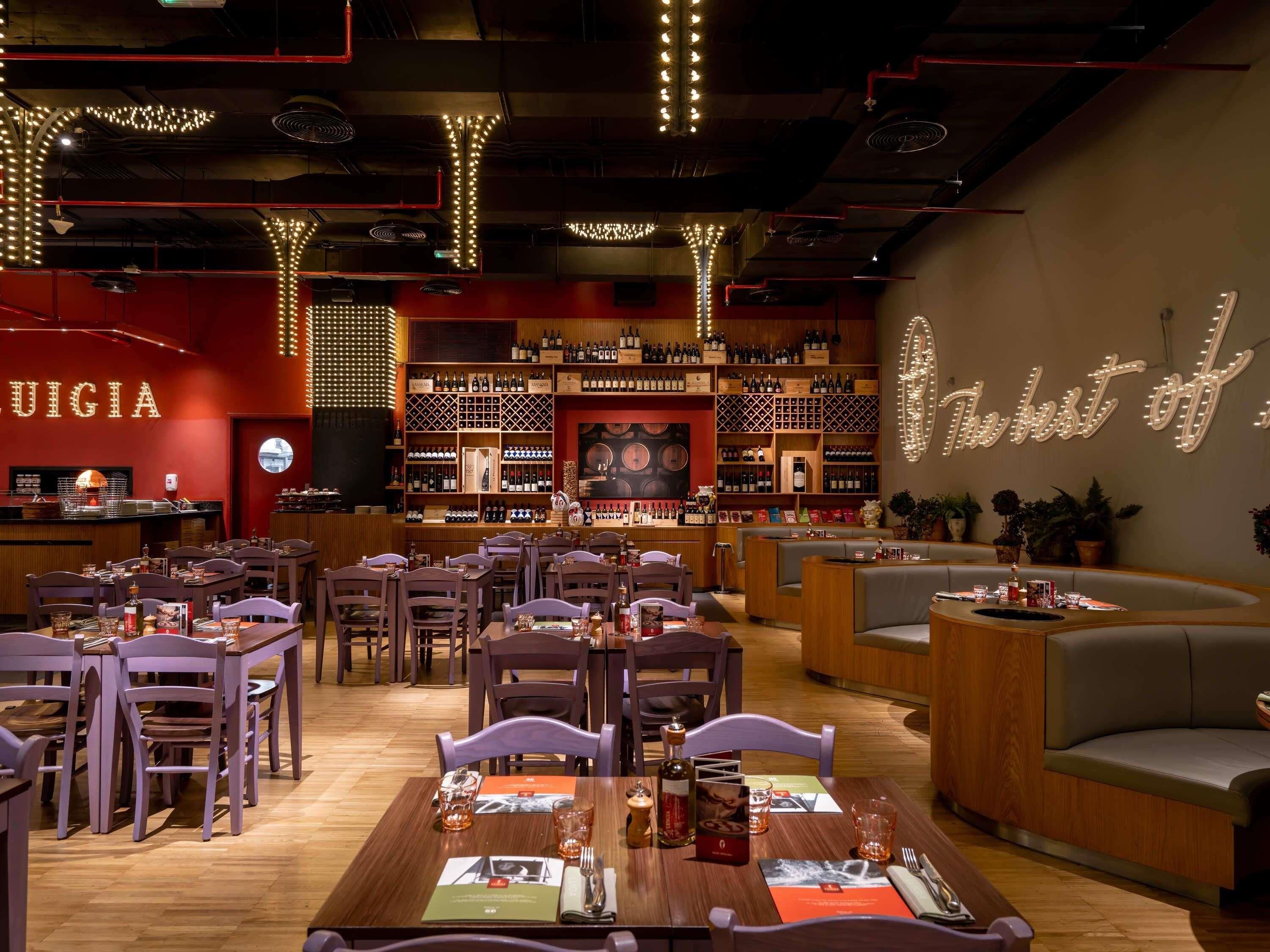 Ein Restaurant mit mehreren Tischen, Stühlen und einer Bar mit Weinflaschen.