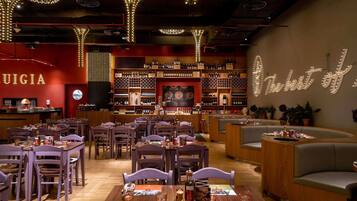 Ein Restaurant mit mehreren Tischen, Stühlen und einer Bar mit Weinflaschen.