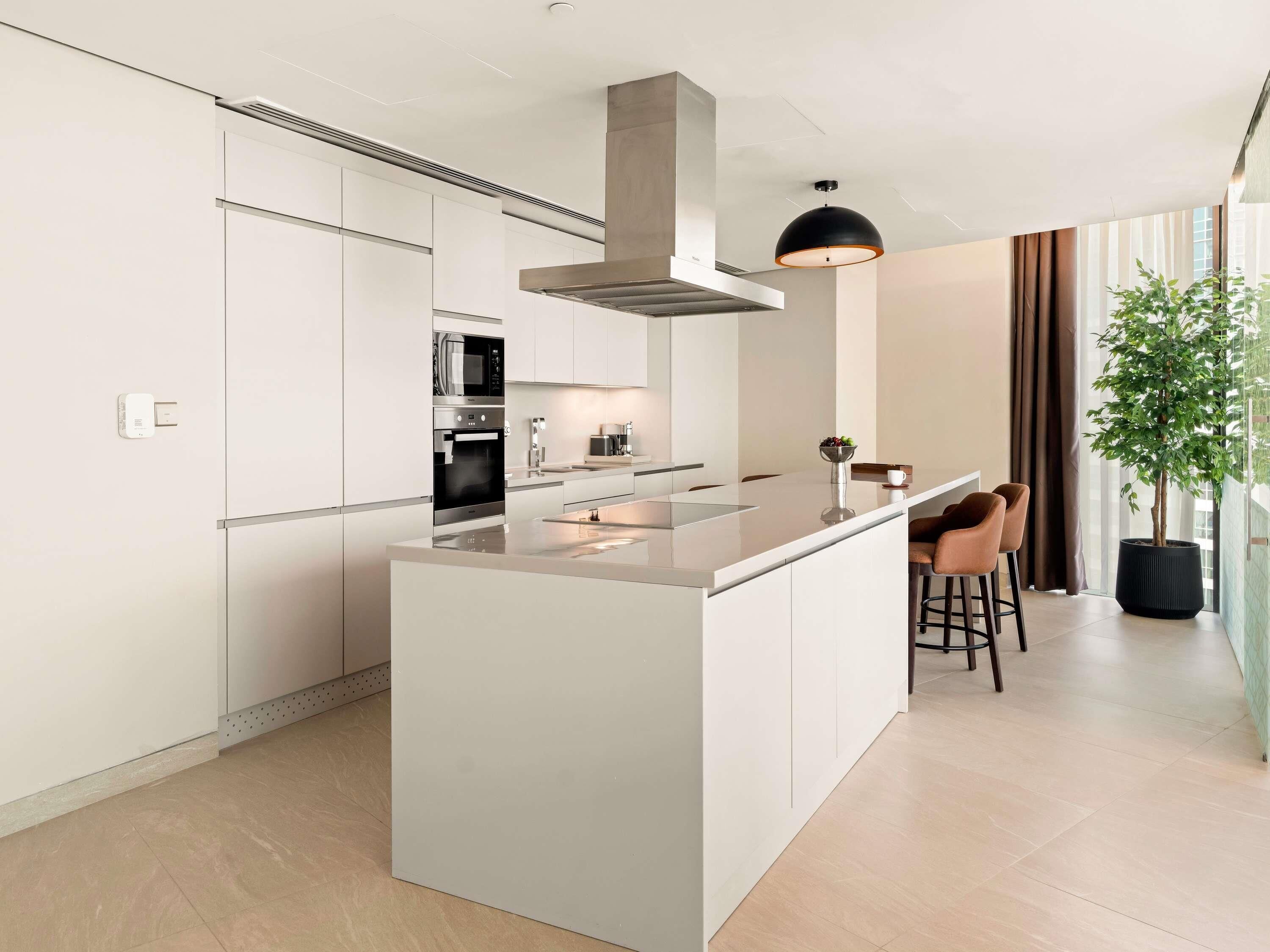 A modern kitchen with a central island, stainless steel appliances, and a pendant light.