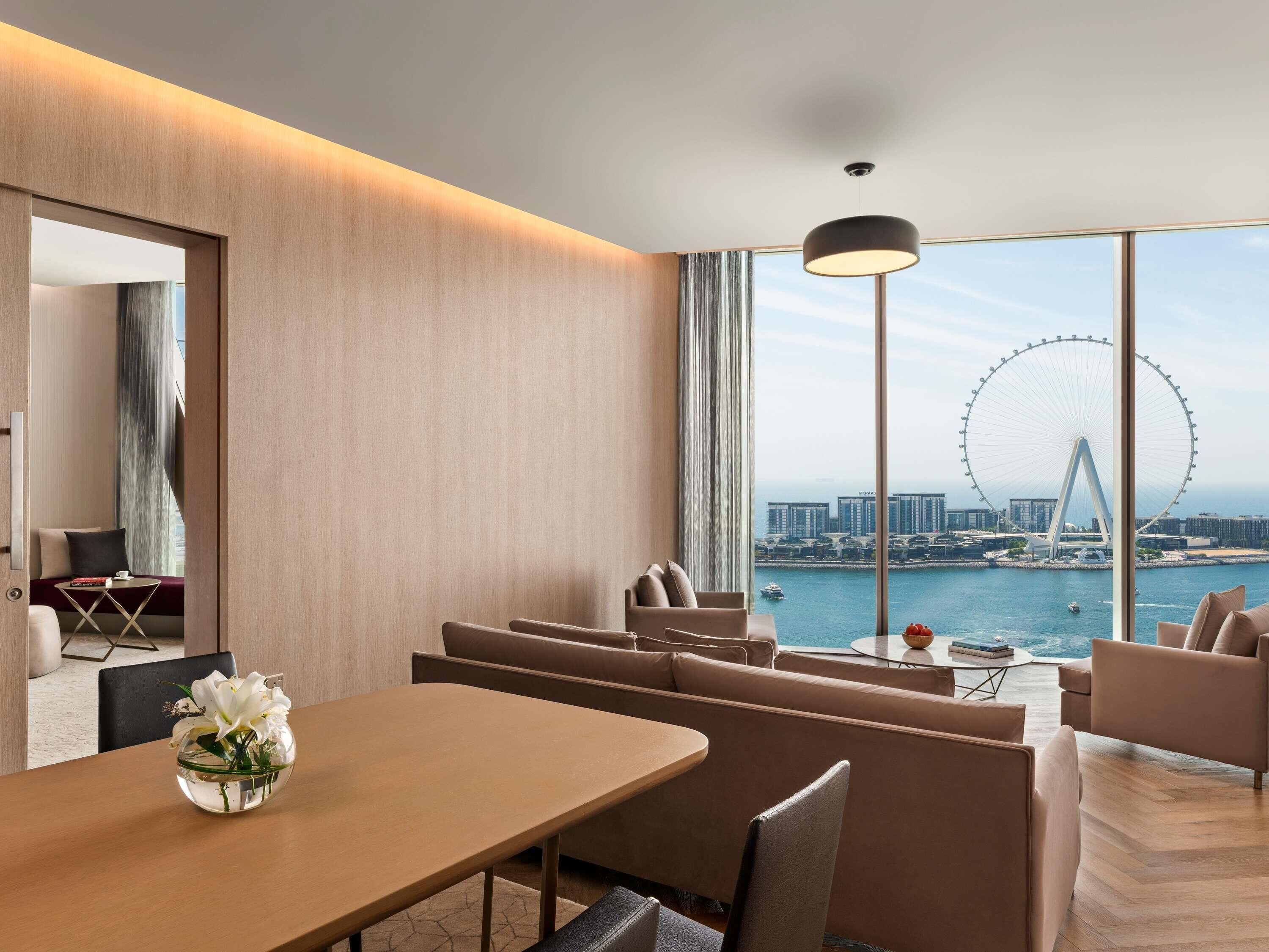 A modern hotel room with a large window offering a view of a Ferris wheel and cityscape.