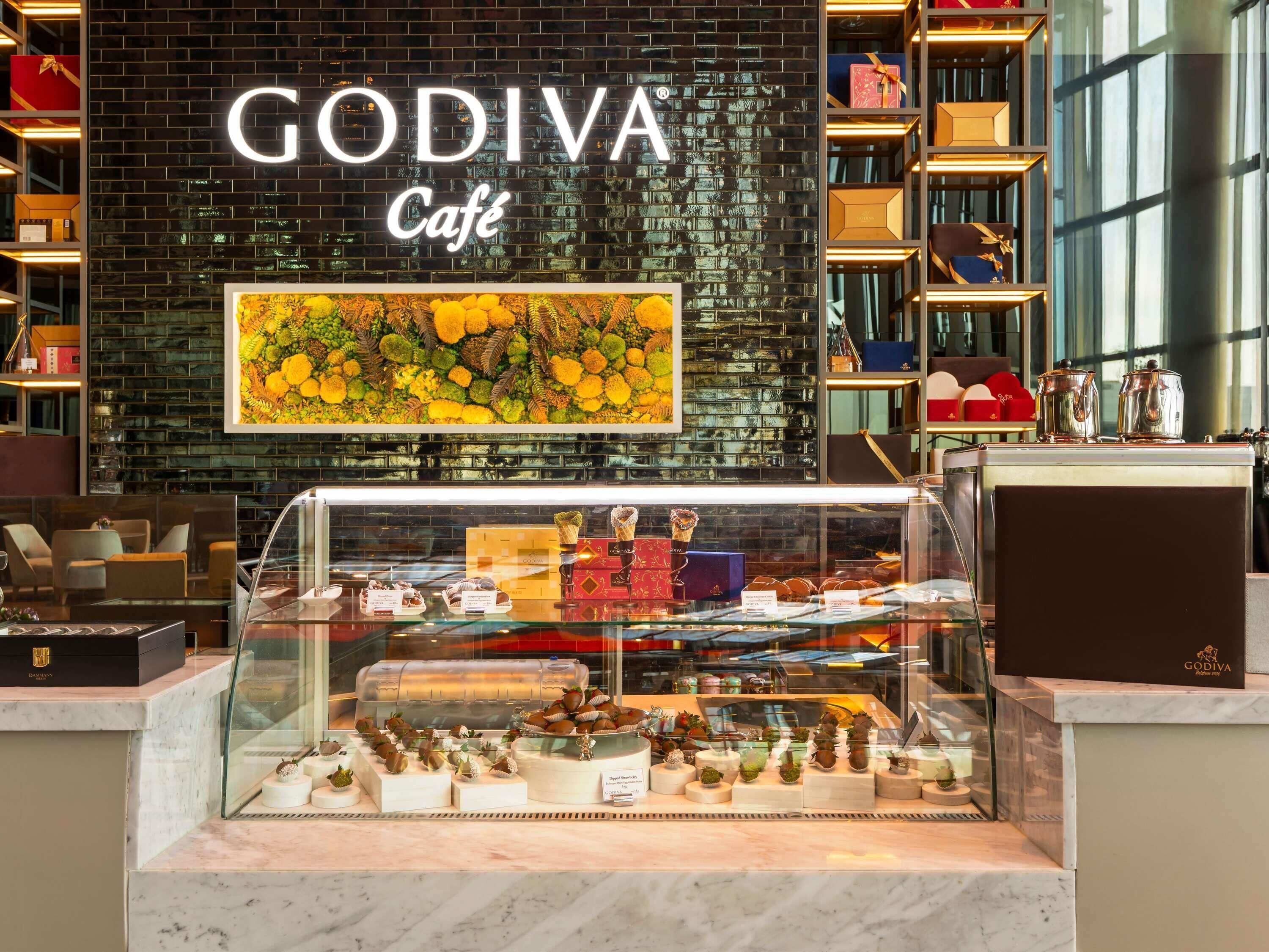 Un Caffè GODIVA con un muro in mattoni e una teca con dolci.
