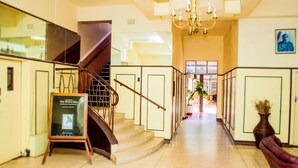 A hotel lobby with a staircase, a reception desk, and a chandelier. - The Grey's Inn (Bulawayo)