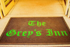 A brown doormat with green text that reads "The Grey's Inn."