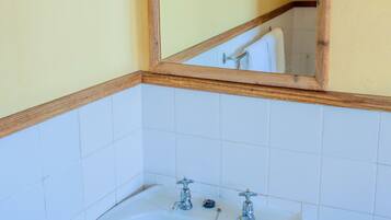 A bathroom with a white sink, wooden frame around the mirror, and yellow walls.