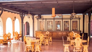 A spacious dining area with wooden tables and chairs, a high ceiling with exposed beams, and framed artwork on the walls. - The Grey's Inn (Bulawayo)