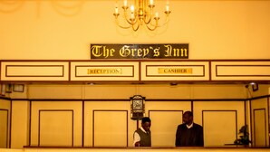 A reception desk at The Grey's Inn with a clock above it. - The Grey's Inn (Bulawayo)