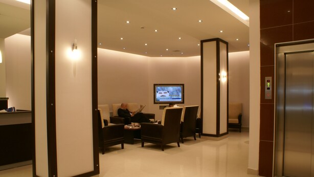A modern lobby with a reception desk, seating area, and a television screen. - Kent Otel (Samsun)