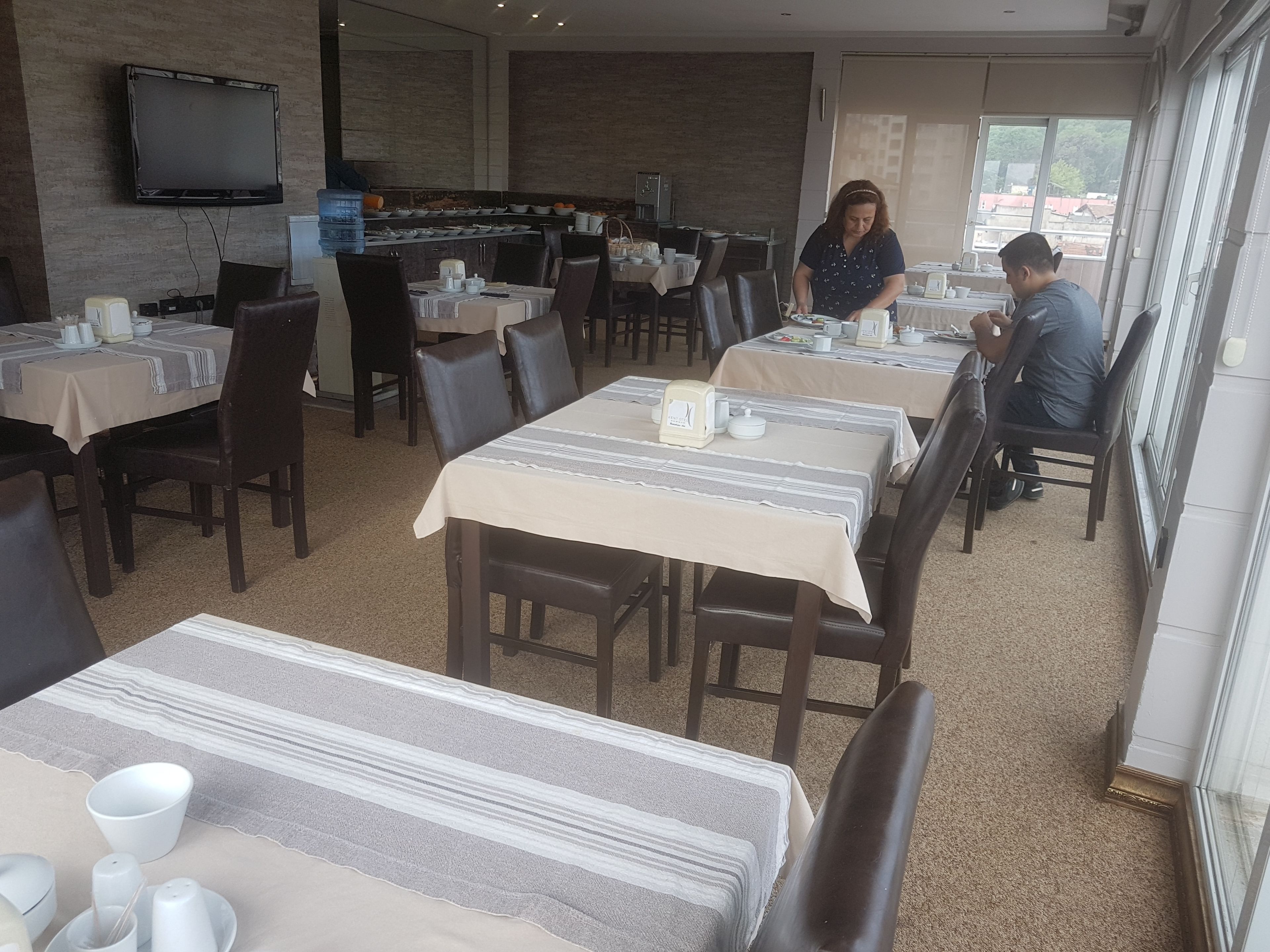 A restaurant with multiple tables, chairs, and a television mounted on the wall.