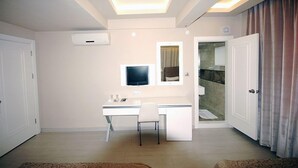 A modern bedroom with a desk, chair, and a television. - Kent Otel (Samsun)