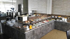 A modern kitchen with a buffet setup, featuring stainless steel appliances, a microwave, and a variety of food items. - Kent Otel (Samsun)