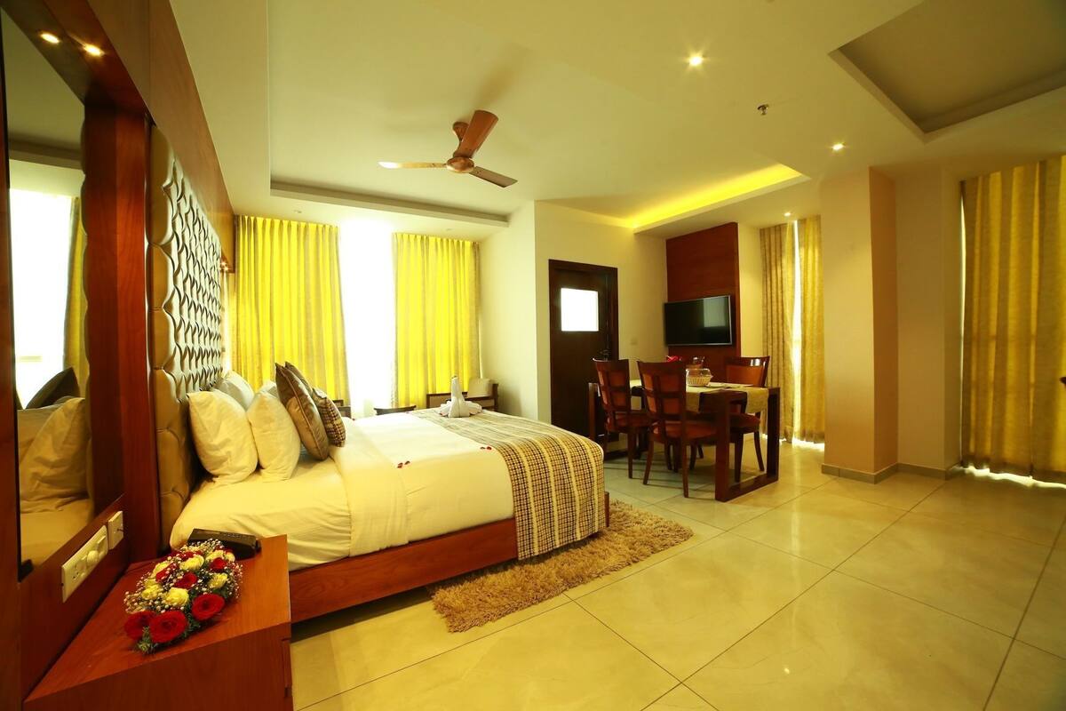 A hotel room with a bed, a desk, a chair, a television, and a ceiling fan.