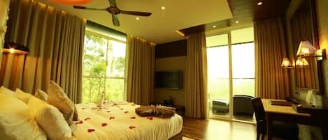 A spacious bedroom with a large bed, a desk, and a view of the outdoors.