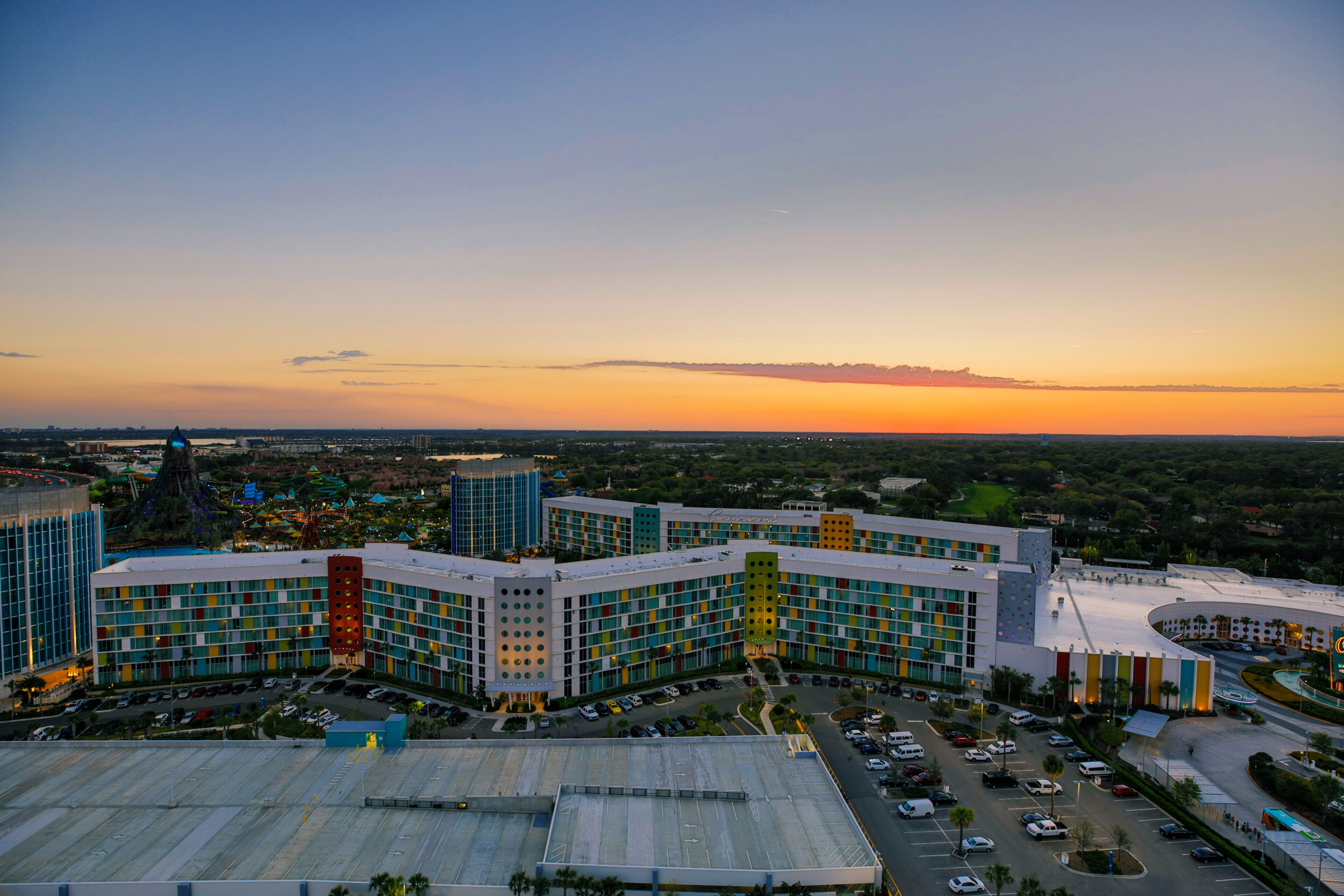 A multi-story hotel with a modern architectural design, featuring a central courtyard and parking facilities.