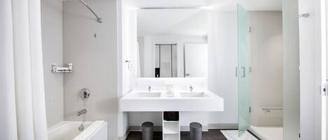 A modern bathroom with a large white sink, a bathtub, and a glass shower enclosure.