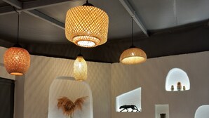 Interior moderno com luminárias suspensas de tecido, janelas com vidro fosco e silhuetas, e uma mesa central com um jogo americano estampado em amarelo.