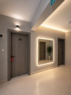 A hallway with three doors, each marked with a number. There is a potted plant on the floor and a wall-mounted mirror. - Soykan Hotel (Marmaris)