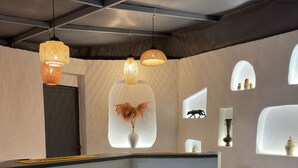 Uma área de bar moderna com banquetas de madeira, um balcão e prateleiras decorativas na parede.