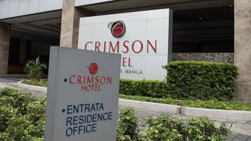 A sign for the Crimson Hotel in Manila, indicating the entrance, residence office, and drop-off lobby.