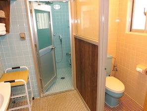 A bathroom with a shower, toilet, and a sink with a towel rack.