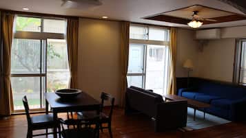 A room with a dining table, chairs, a sofa, and a ceiling fan.
