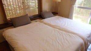 Un lit double avec du linge de lit blanc, une table de chevet et une lampe.