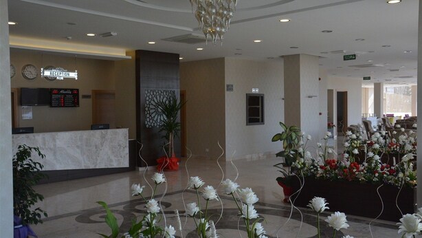 Zona de recepción con mostrador de mármol, pantalla digital y candelabro.