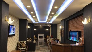 Un vestíbulo de hotel con mostrador de recepción, zona de estar y chimenea.