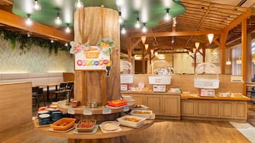 A buffet setup with a central wooden tree trunk, various food dishes, and a sign indicating a coffee station.