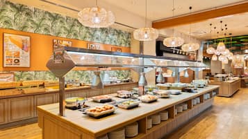 A buffet setup with various food items and a tropical wallpaper design.