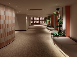 Un pasillo de hotel con una pared curva, una zona de estar y una decoración de plantas.