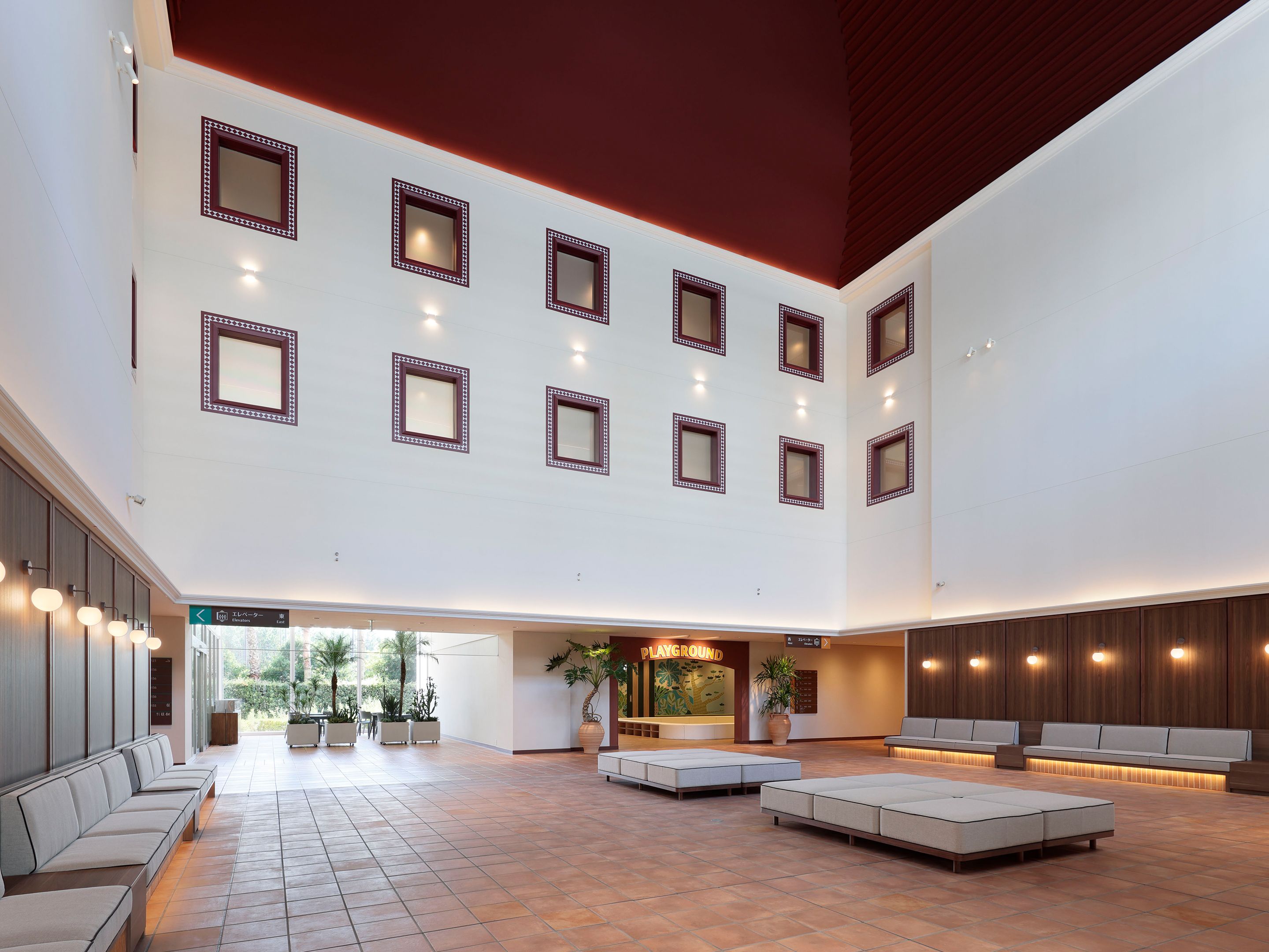 A spacious lobby with multiple seating areas, a reception desk, and a children's play area.