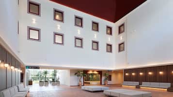 A spacious lobby with multiple seating areas, a reception desk, and a children's play area.