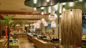 Un restaurante con mostrador de madera, diversas opciones de comida e iluminación colgante.