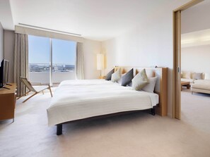 Habitación de hotel con una cama grande, televisión, una silla y vistas a la ciudad.