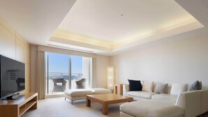 Una habitación de hotel moderna con televisión de pantalla plana, un sofá, una mesita de centro y un balcón con vistas a la ciudad.
