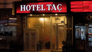 A hotel named 'HOTEL TAC' with a crown symbol above the name, a visible entrance, and a sign indicating a price of 31000.00.