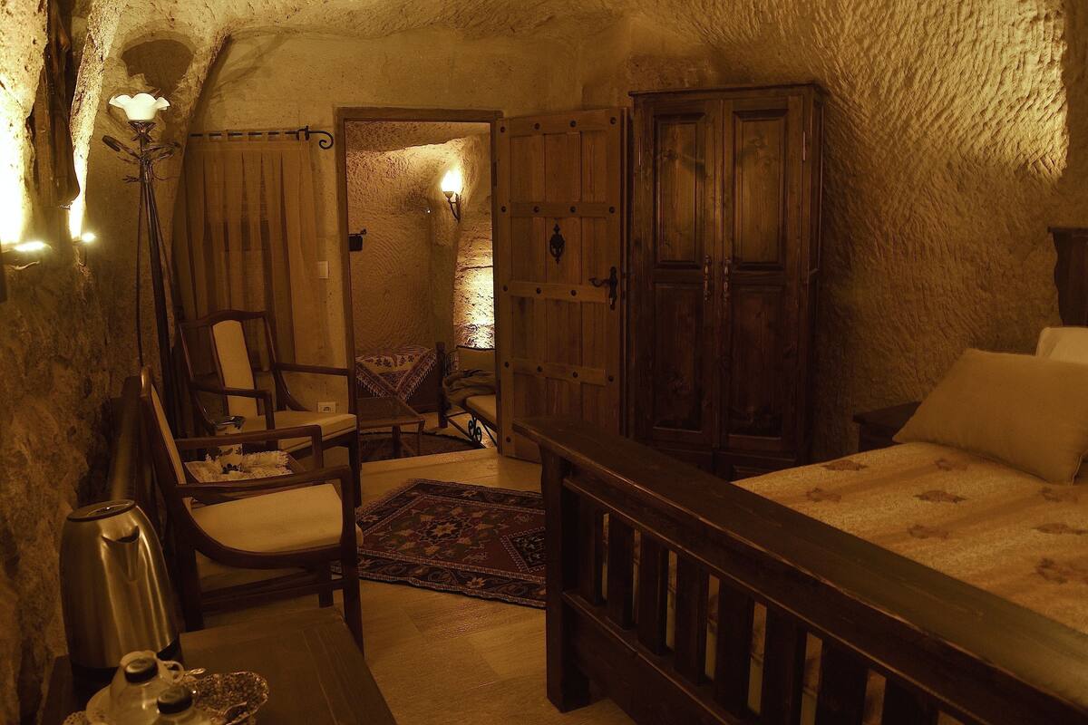 A cozy room with a bed, a chair, a table with a kettle, and a wardrobe.