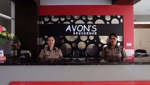 Una mesa de recepción con un cartel que dice "AVON'S RESIDENCE" y dos empleados.