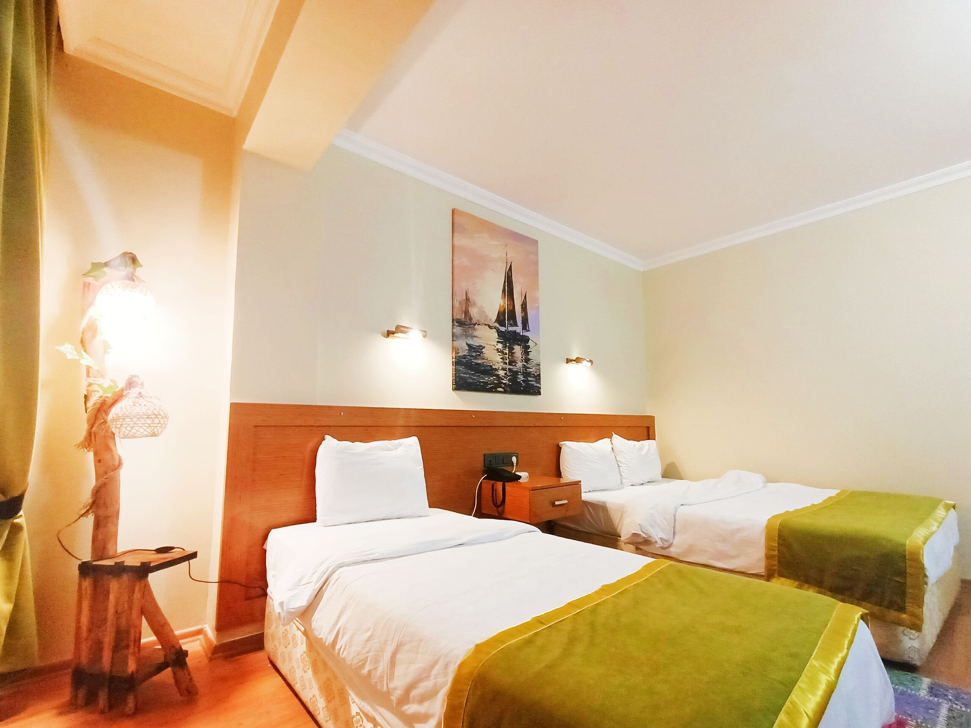 Une chambre d’hôtel avec deux lits, une tête de lit en bois, un tableau accroché au mur et une petite table avec une lampe.